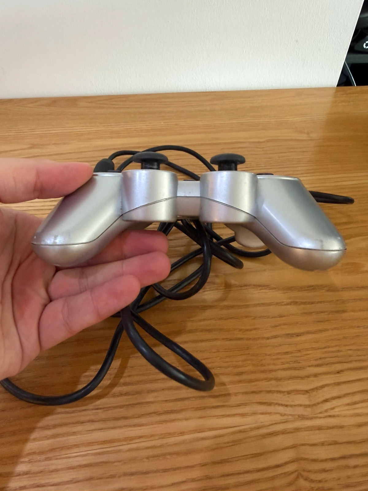 Sony silver PlayStation 2 controller with wired connection and minimal cosmetic wear.