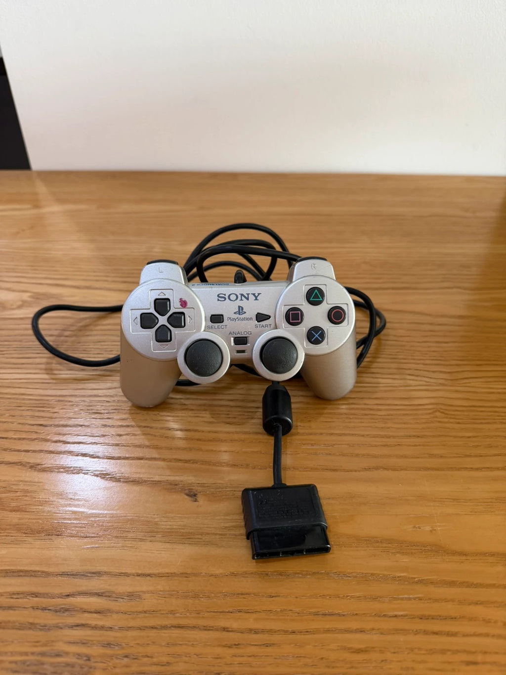 Sony silver PlayStation 2 controller with wired connection and light signs of use.