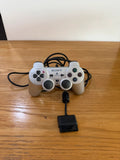 Sony silver PlayStation 2 controller with wired connection and light signs of use.