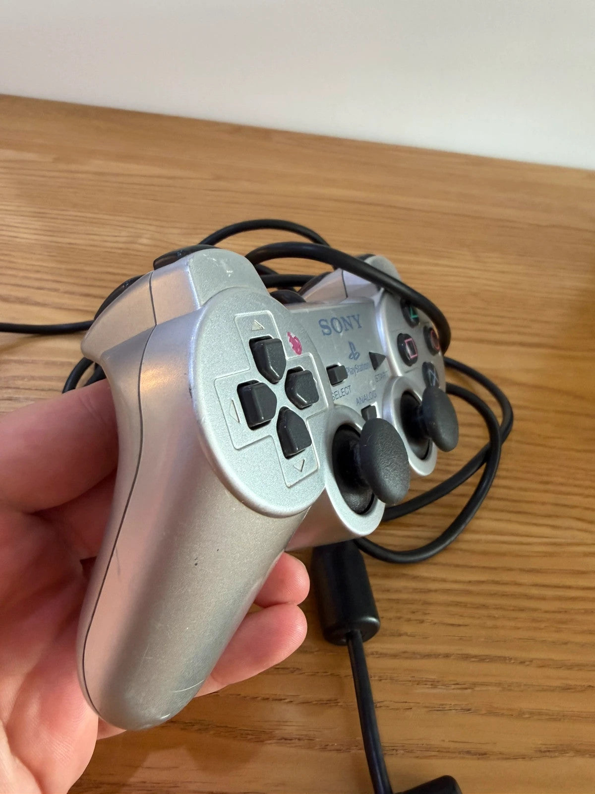 Sony silver PlayStation 2 controller with wired connection and light signs of use.