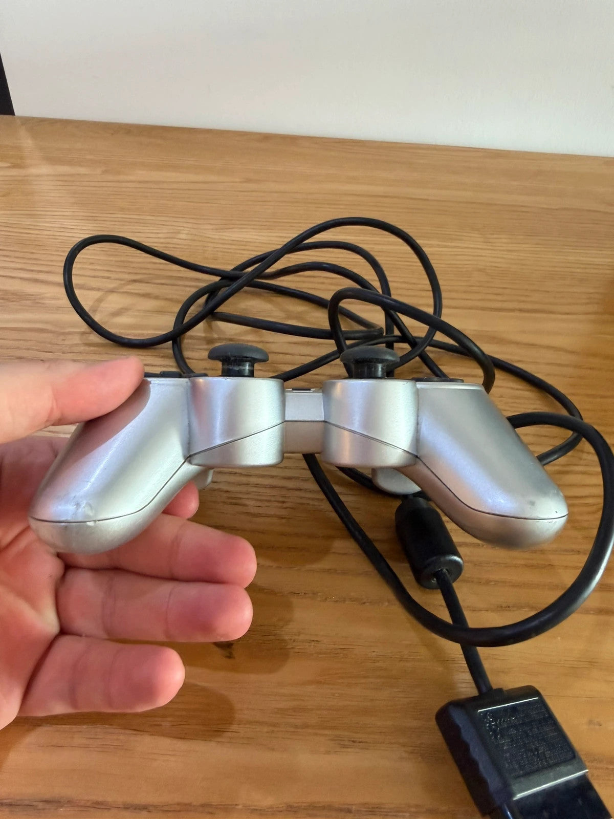 Sony silver PlayStation 2 controller with wired connection and light signs of use.