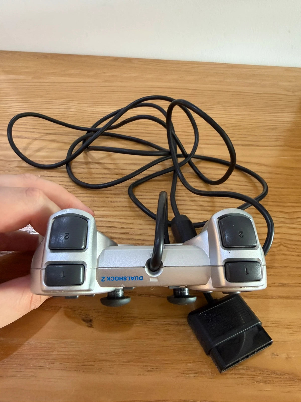 Sony silver PlayStation 2 controller with wired connection and light signs of use.