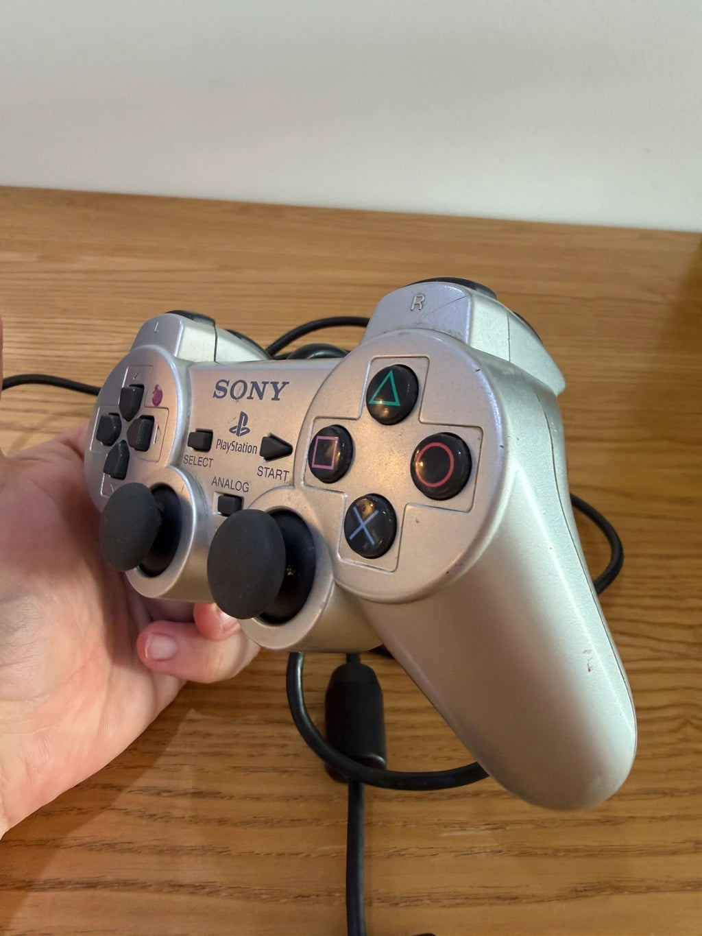 Sony silver PlayStation 2 controller with wired connection and light signs of use.