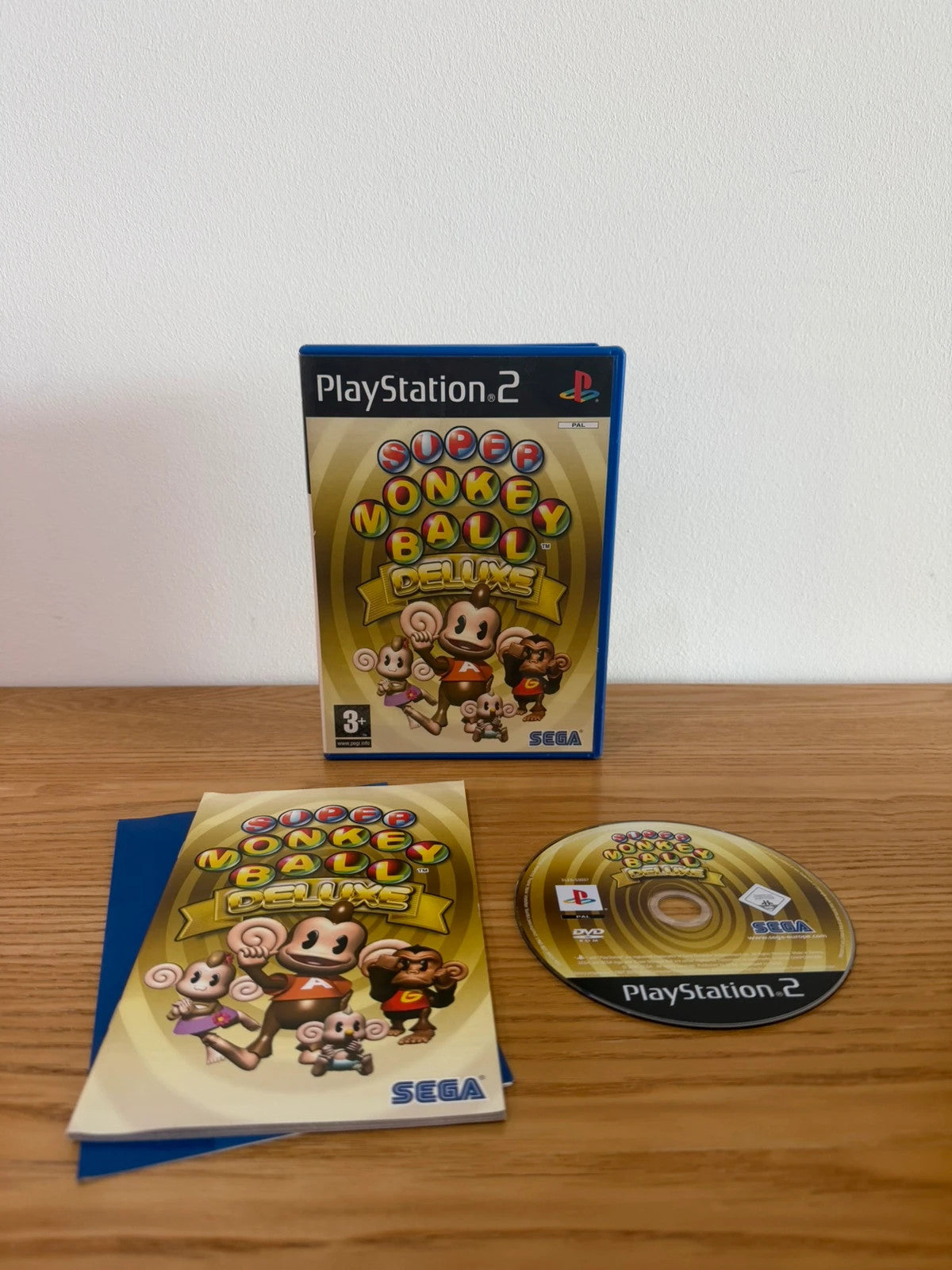 Multiples cream video game accessory with Super Monkey Ball Deluxe cover art and manual.