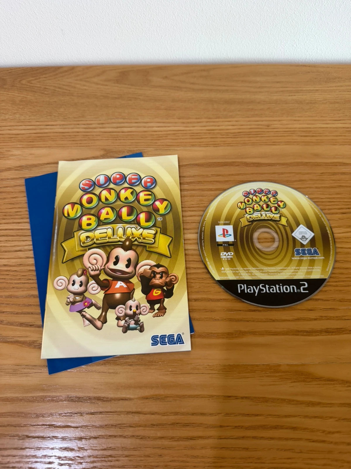Multiples cream video game accessory with Super Monkey Ball Deluxe cover art and manual.
