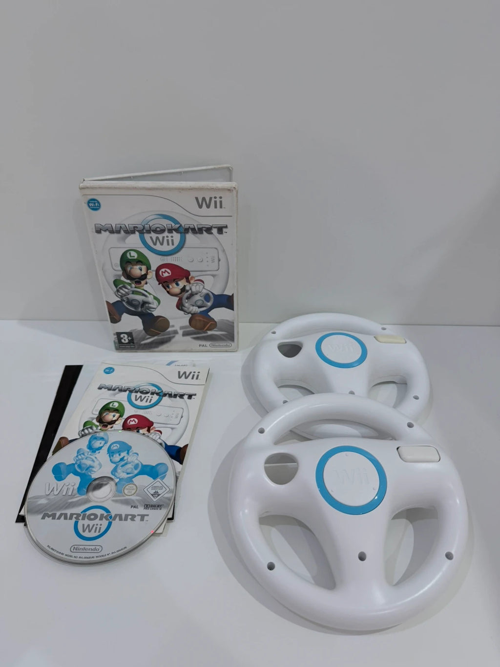 Nintendo Mario Kart Wii video game with case, manual, and two official steering wheels.