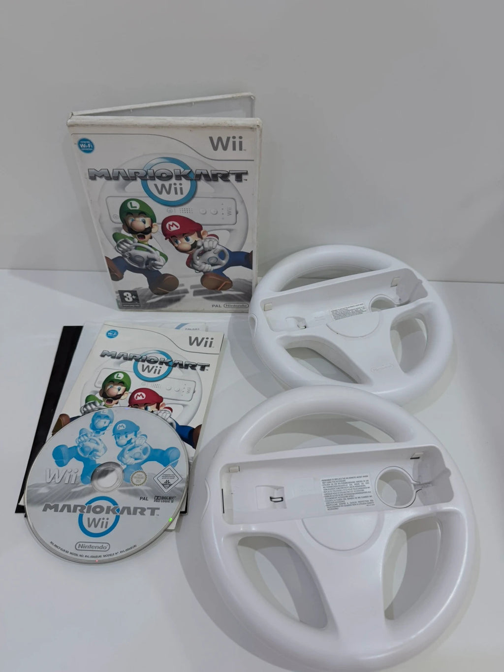 Nintendo Mario Kart Wii video game with case, manual, and two official steering wheels.
