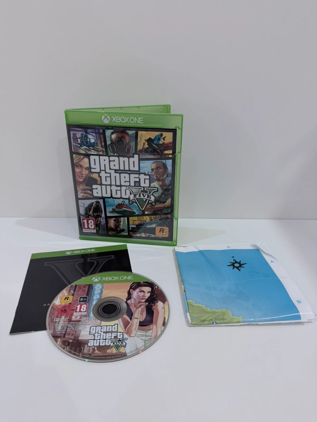 Grand Theft Auto V Xbox One game case with disc, manual, and map included.
