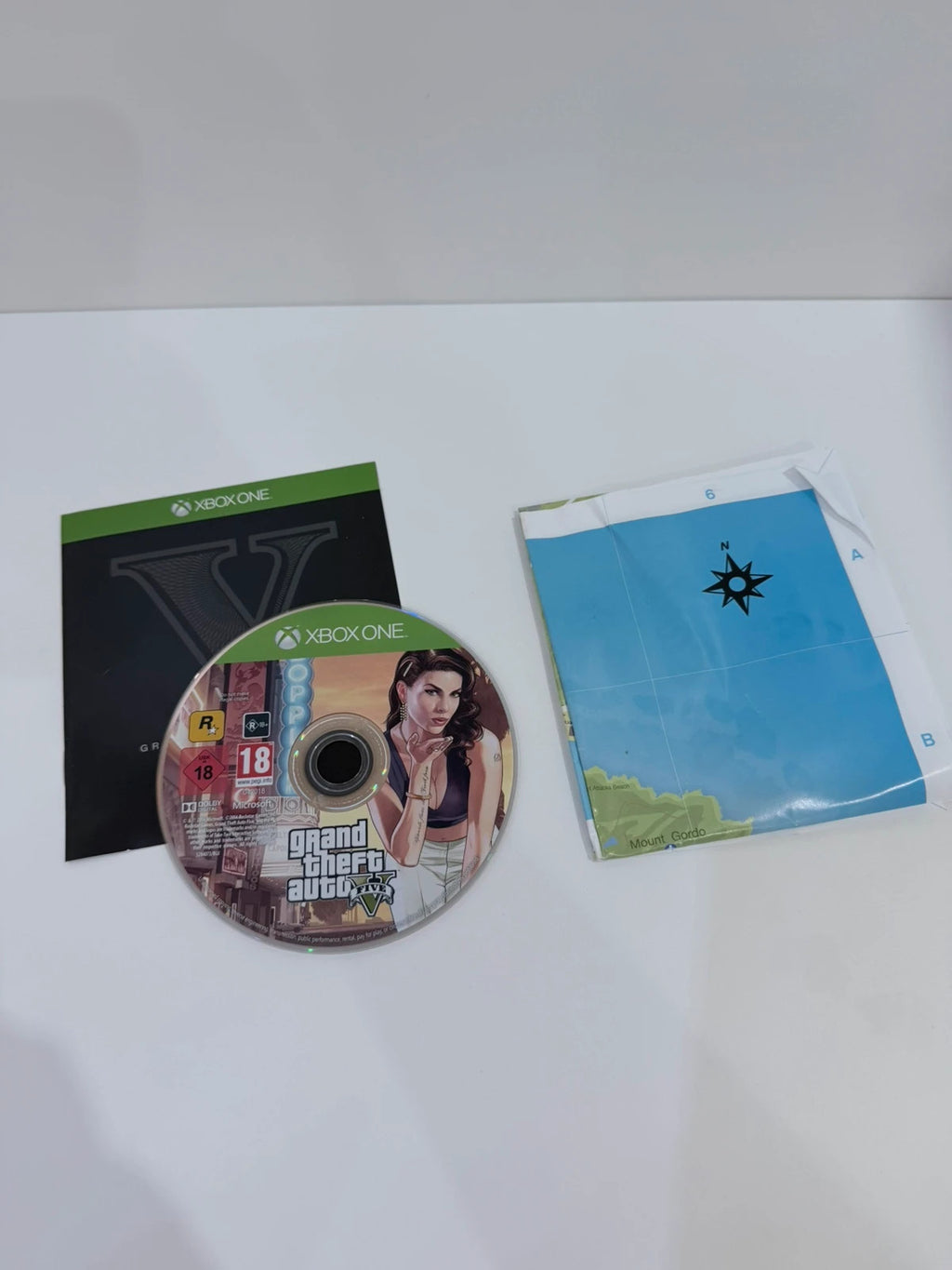 Grand Theft Auto V Xbox One game case with disc, manual, and map included.