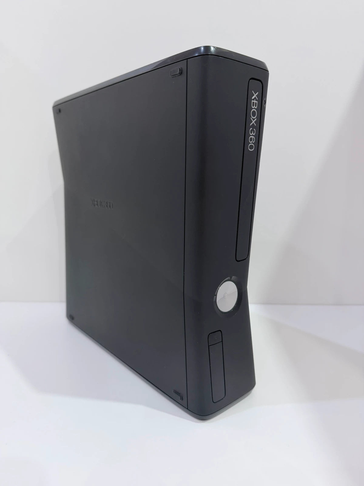 Xbox black video game console with white official controller and power supply cables.