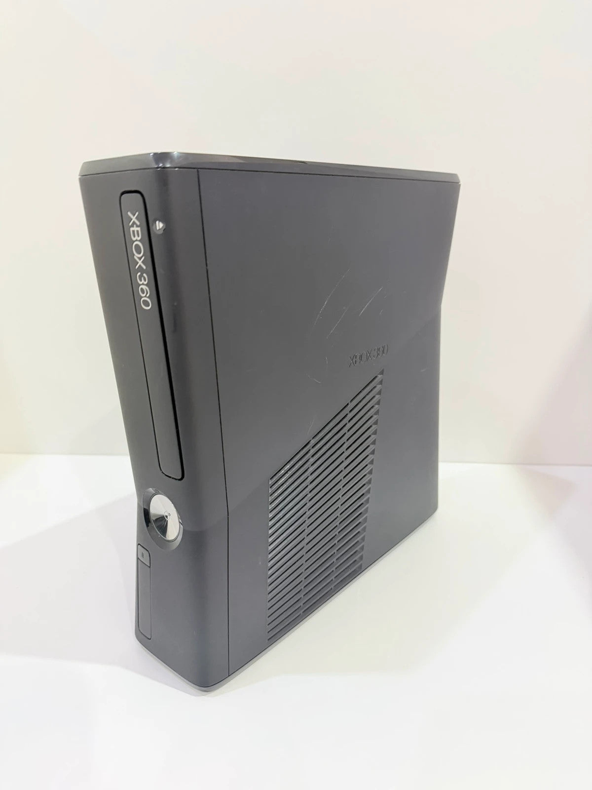 Xbox black video game console with white official controller and power supply cables.