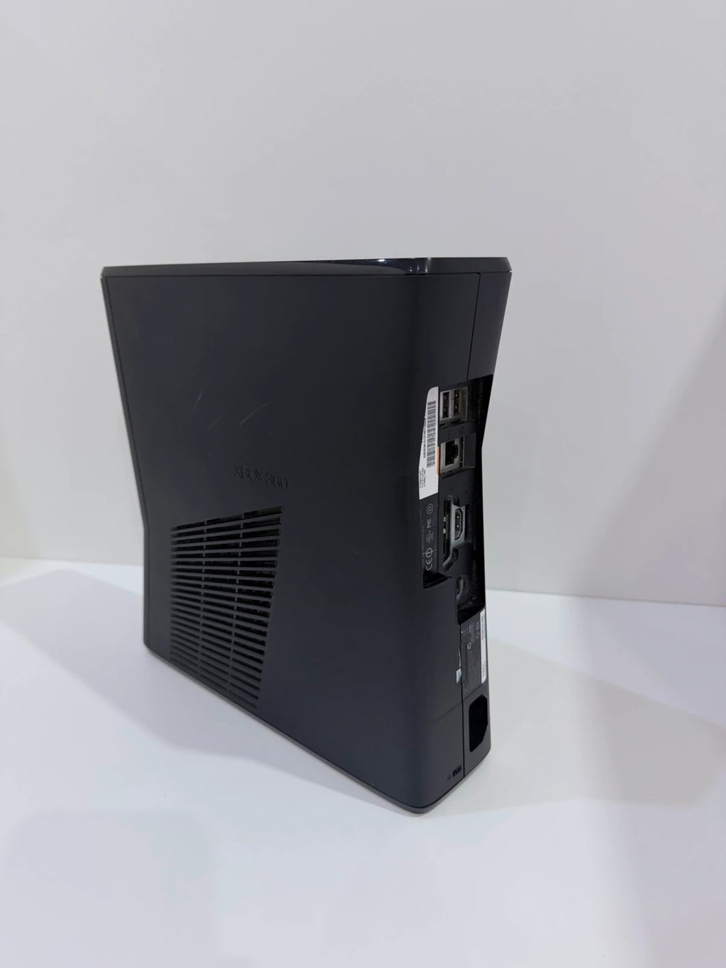 Xbox black video game console with white official controller and power supply cables.