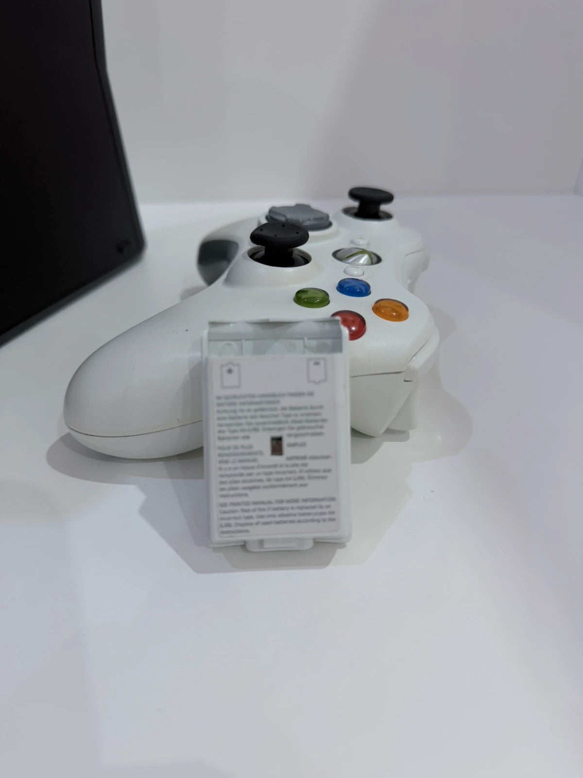 Xbox black video game console with white official controller and power supply cables.