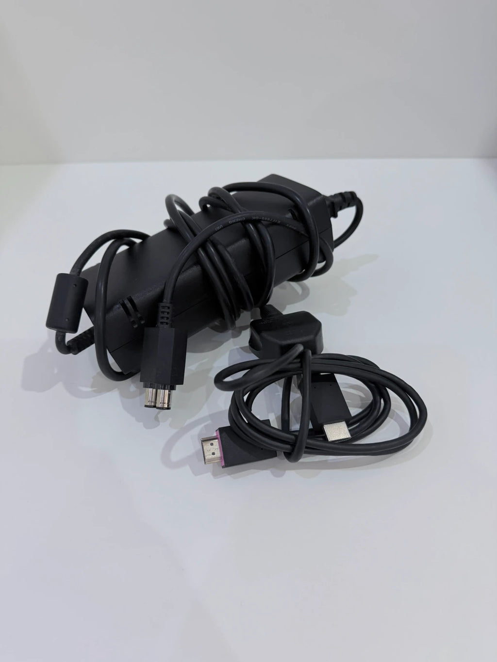 Xbox black video game console with white official controller and power supply cables.