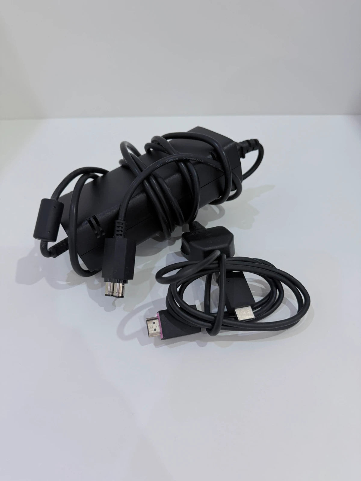 Xbox black video game console with white official controller and power supply cables.