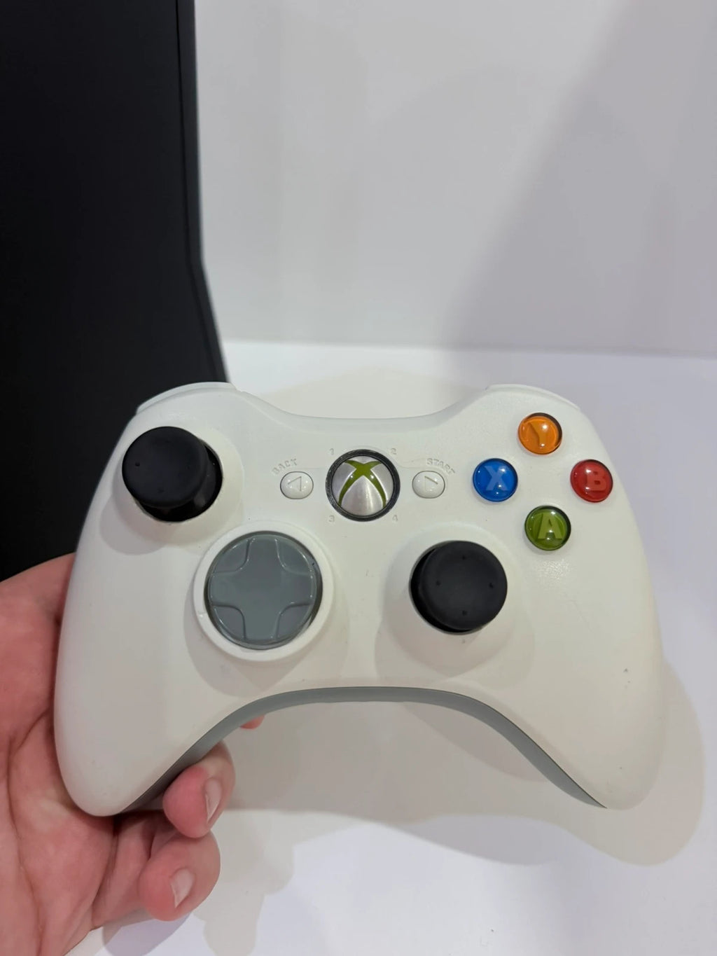Xbox black video game console with white official controller and power supply cables.