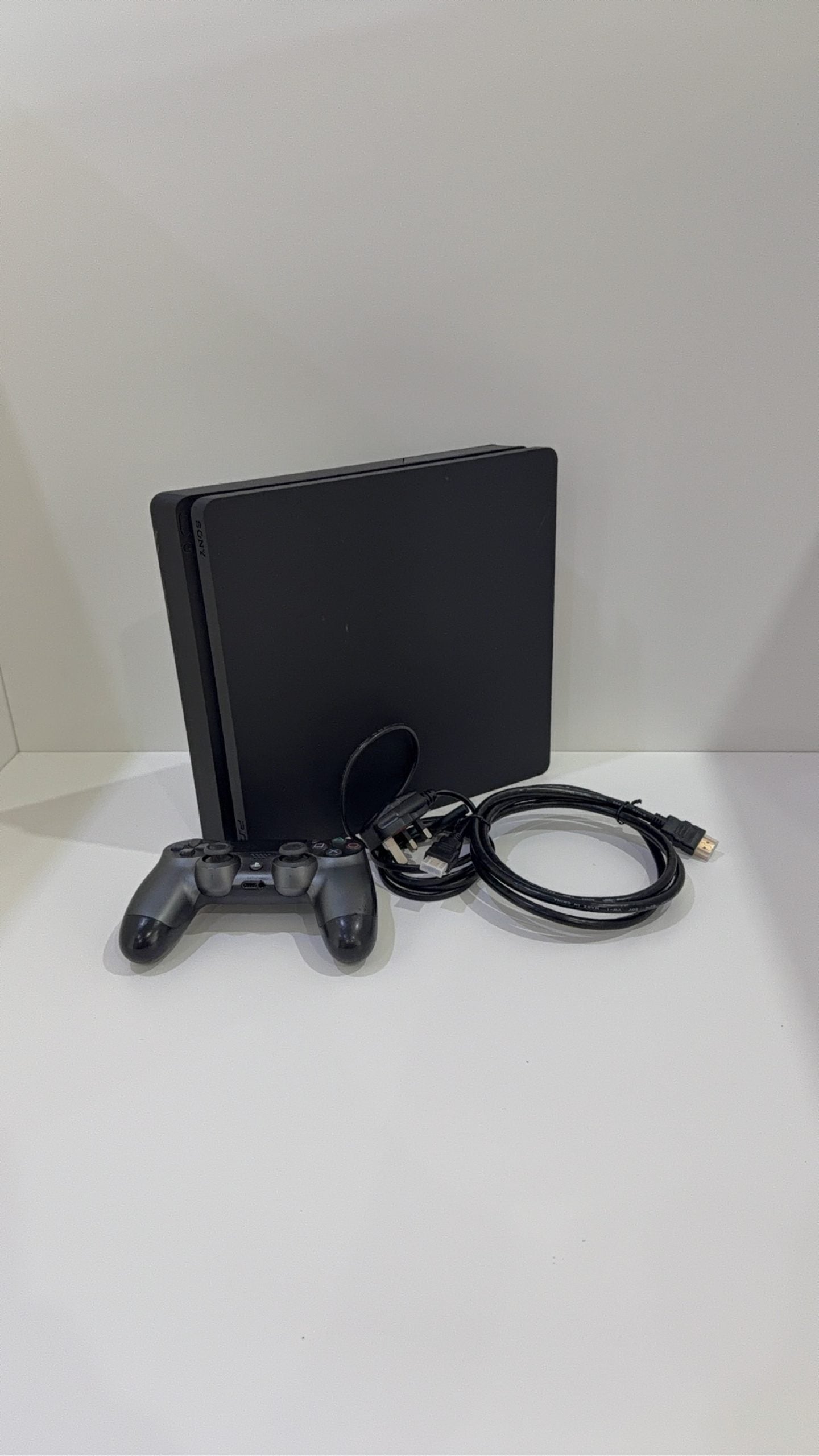 Sony PlayStation 4 Slim 500GB black console with one controller, power and HDMI cables.