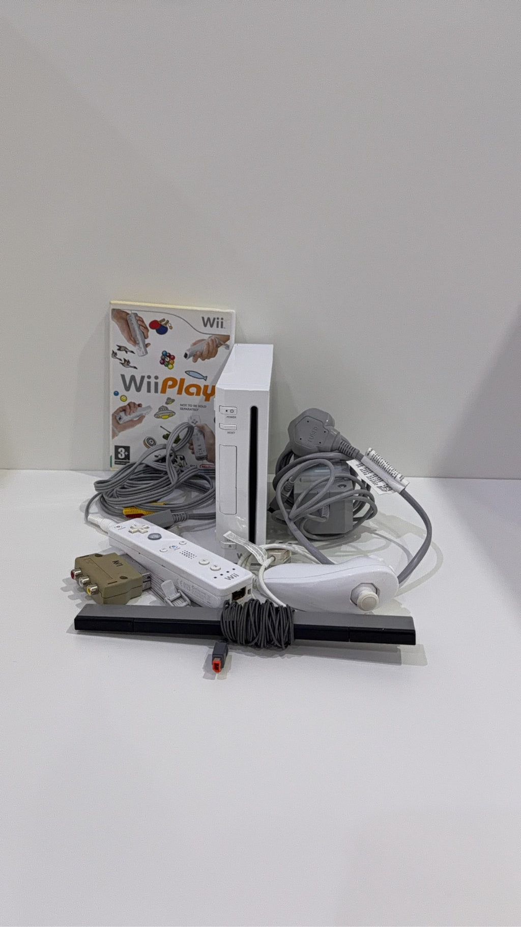 White Nintendo Wii console bundle with official Wii Remote, Nunchuk, cables, and Wii Play game.