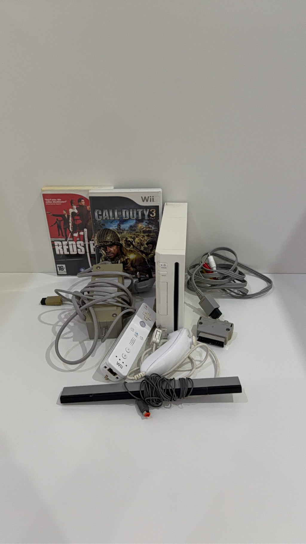White Nintendo Wii console bundle with official Wii Remote, Nunchuk, and two boxed games.
