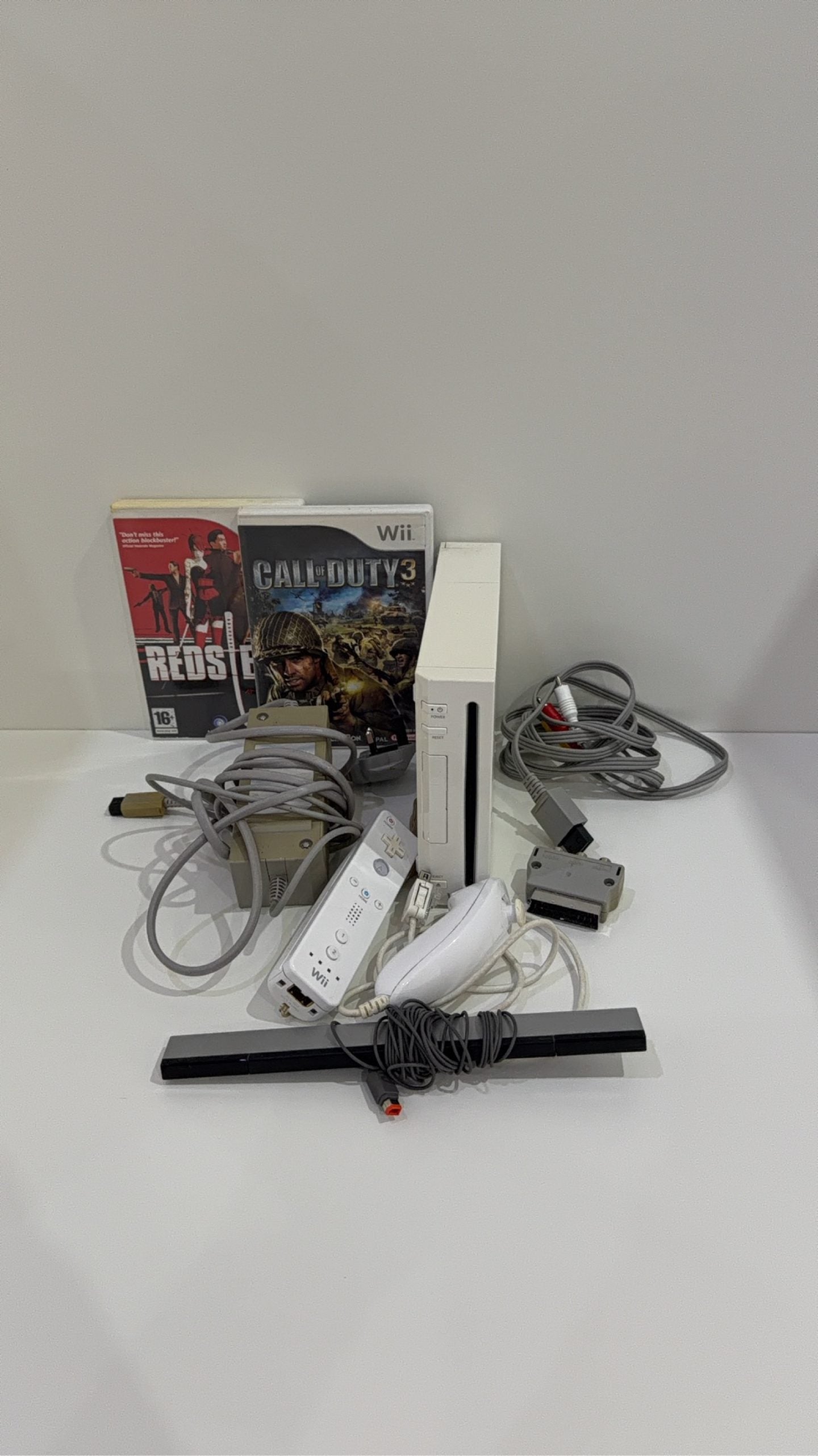 White Nintendo Wii console bundle with official Wii Remote, Nunchuk, and two boxed games.