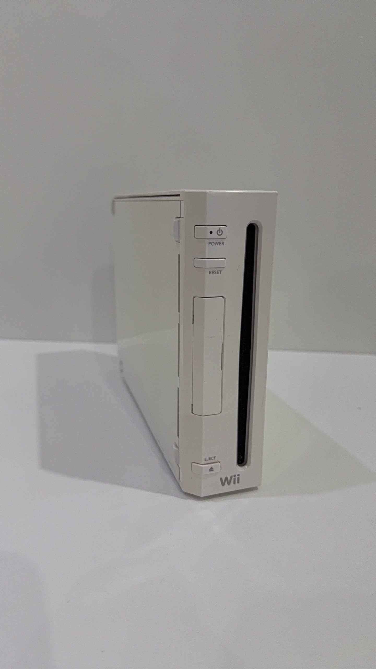 White Nintendo Wii console bundle with official Wii Remote, Nunchuk, and two boxed games.