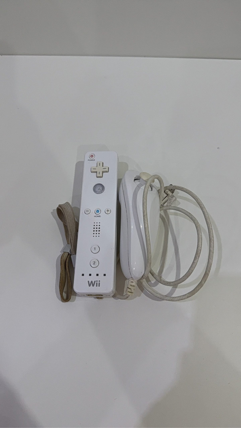 White Nintendo Wii console bundle with official Wii Remote, Nunchuk, and two boxed games.