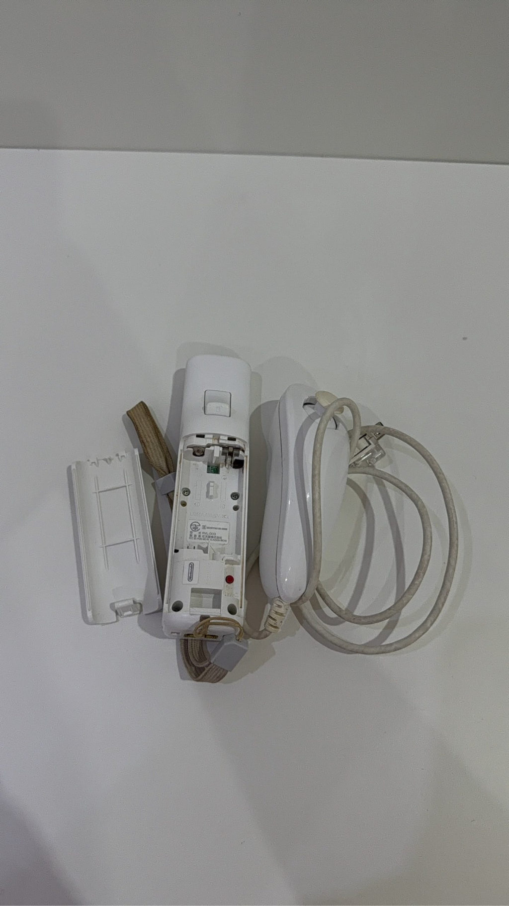 White Nintendo Wii console bundle with official Wii Remote, Nunchuk, and two boxed games.